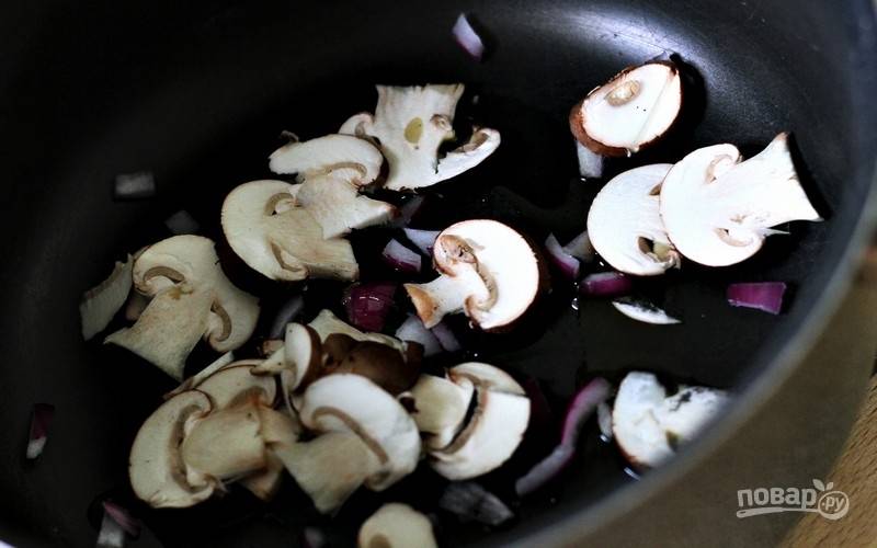 В глубокой сковороде в небольшом количестве оливкового масла обжарьте нарезанный лук и нарезанные шампиньоны.