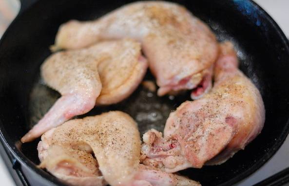 В сковороду с толстыми стенками (желательно чугунную) наливаем немного растительного масла, ставим на сильный огонь. Когда масло хорошенько прогреется, выкладываем на сковороду кусочки курицы.