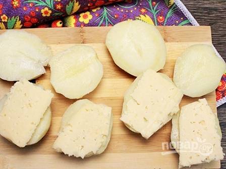 Сыр нарезаем пластинками и выкладываем на одну половинку картофеля.