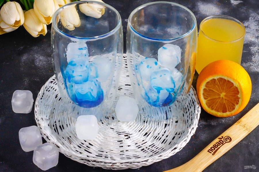 Влейте в стаканы сироп "Блю Кюрасао". Если его нет в наличии, то замените сироп сахарным сиропом и всыпьте в каждую емкость по щепотке синего пищевого красителя.