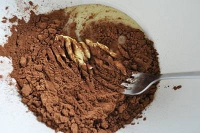В небольшой миске смешаем сгущенку, половину необходимого какао и сливочное масло. Тщательно перемешаем ложкой до состояния шоколадной пасты. 
