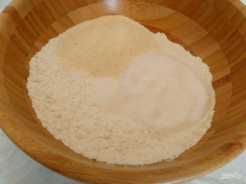 В глубокой миске соедините сухие компоненты: просеянную муку (200г), манную крупу, сахар (50г), щепотку соли и ванильный сахар.