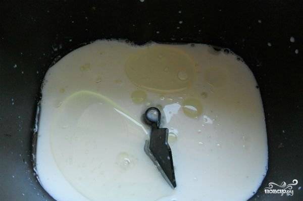 В чашу хлебопечки влейте 30 мл растительного масла. Молоко подогрейте и добавьте к маслу.