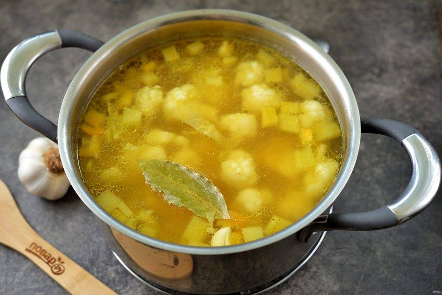 Долейте воды до верха кастрюли, выложите лавровый лист, посолите и поперчите по вкусу, всыпьте порошок куркумы, варите суп еще 5 минут.