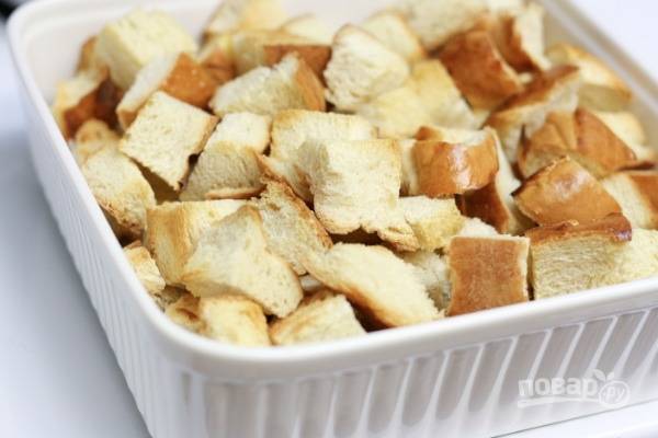 1.	Кусочки белого хлеба нарежьте кубиками (1 см), чтобы получилось около 5 стаканов. Выложите на противень и отправьте в духовку, запекайте при 180 градусах 8-10 минут. Выложите подсушенный хлеб в форму для выпекания.