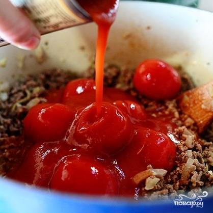 Затем добавляем к фаршу помидоры в собственном соку и томатную пасту. Добавляем специи, перемешиваем и тушим еще 5-6 минут на среднем огне до загустения соуса.