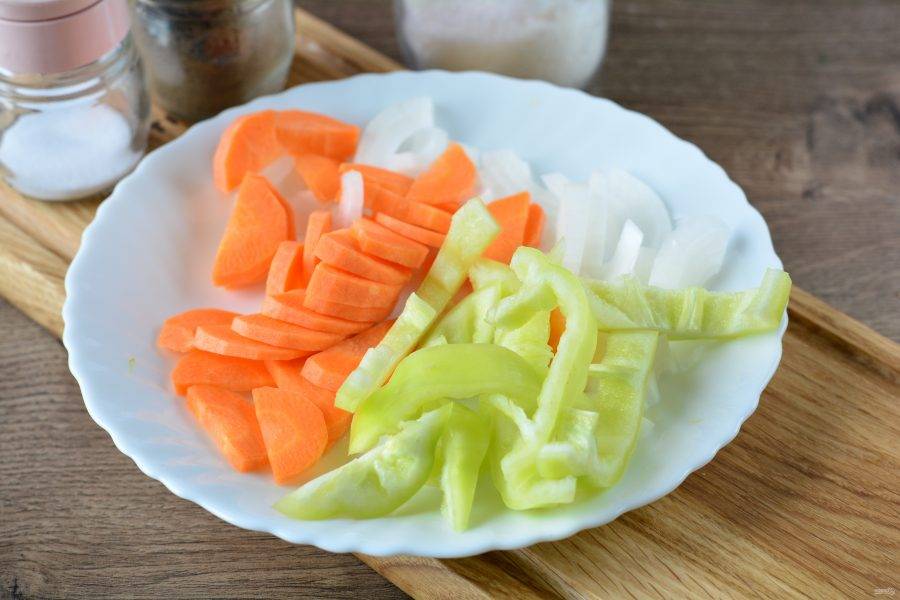 Почистите морковку, лук и сладкий перец. Нарежьте все овощи полукольцами.
