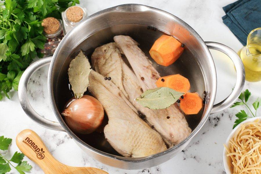 Мясо промойте под проточной водой и удалите остатки перьев, если такие имеются. Морковь очистите, с луковицы снимите верхнюю шелуху и хорошо промойте. Переложите гуся и овощи в кастрюлю. Добавьте воду, лавровый лист и перец горошком. Доведите до кипения, снимите пену и варите на небольшом огне около 1-1,5 часов (до готовности мяса).