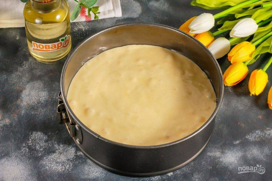 Разогрейте духовку до 180 градусов и смажьте форму для выпекания растительным маслом. Выложите в нее бисквитное тесто и аккуратно разровняйте. Отправьте форму в духовку.