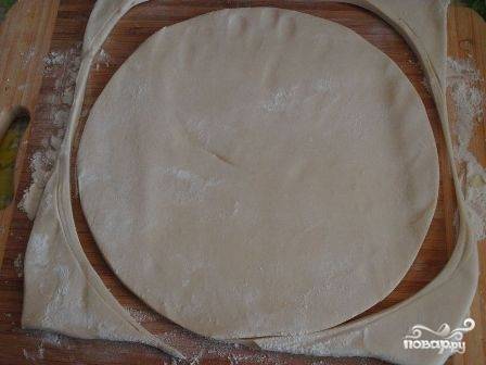 Слегка раскатаем тесто, оно не должно быть очень тонким. Вырезаем круг по размеру формы - 26-28 см.