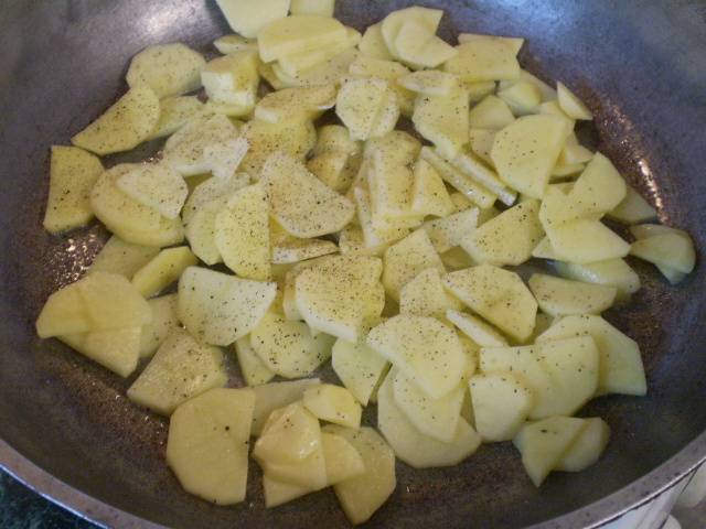 На сковороде разогрейте масло. Добавьте картофель, соль, перец черный молотый. Жарьте до полуготовности, переворачивая время от времени лопаткой, чтобы не пригорело. 
