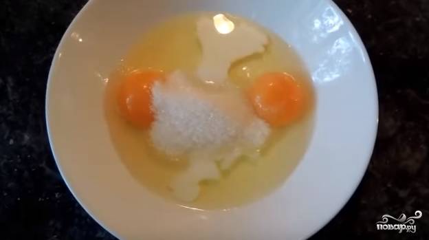 В миске смешайте два яйца с молоком. Добавьте сахар и соль по вкусу. Взбейте венчиком или вилкой.