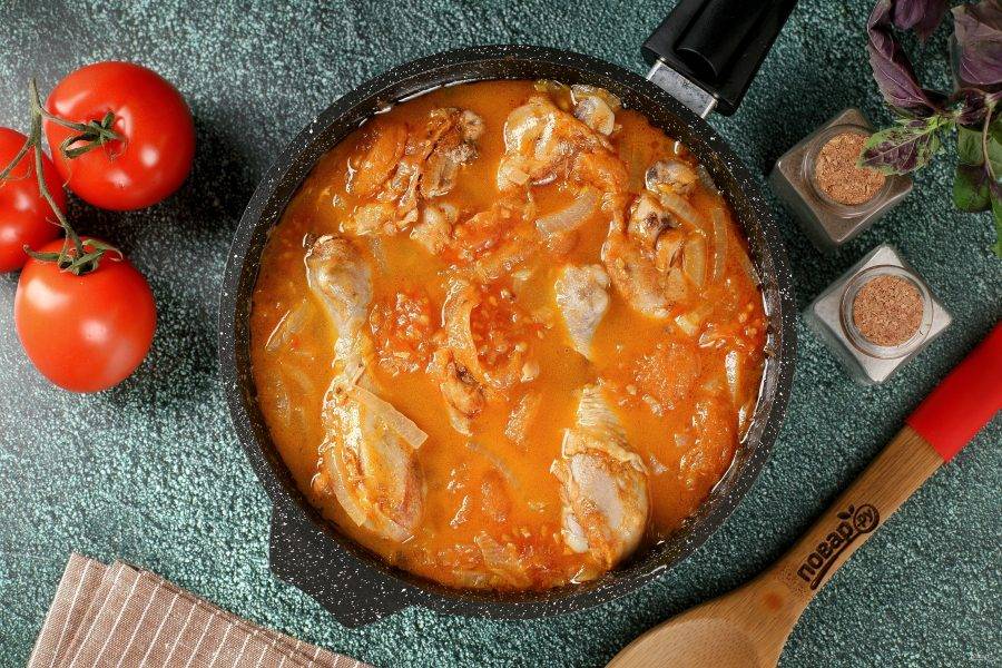 Курица в соусе подливы с помидорами, луком и чесноком на сковороде