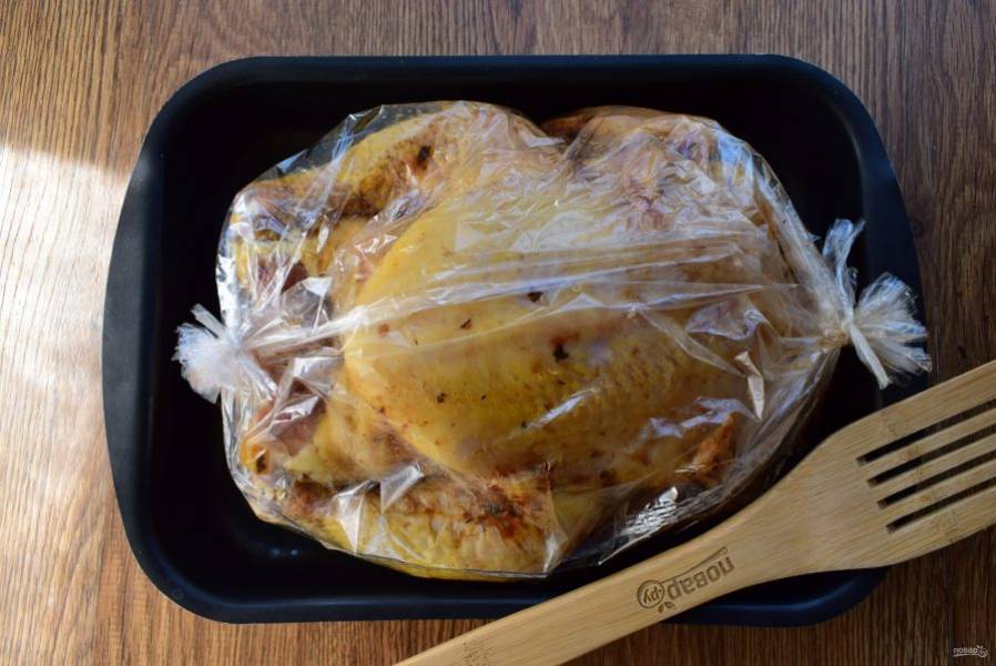 Поместите  маринованную курицу в рукав для запекания, закрепите его концы. Поставьте запекаться в разогретую духовку при 200 °С на 1 час. Снизьте температуру до 180 °С,  разрежьте верх рукава, полейте тушку вытопившимся жиром. Продолжайте запекать курицу до румяной корочки и готовности примерно 40 минут, время зависит от веса курицы.  При небольшом разрезе тушки выделяющийся сок должен быть прозрачным.