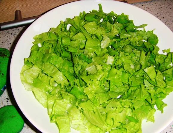 В блюдо для салата выложите ингредиенты слоями. Сначала слой из листьев салата. 
