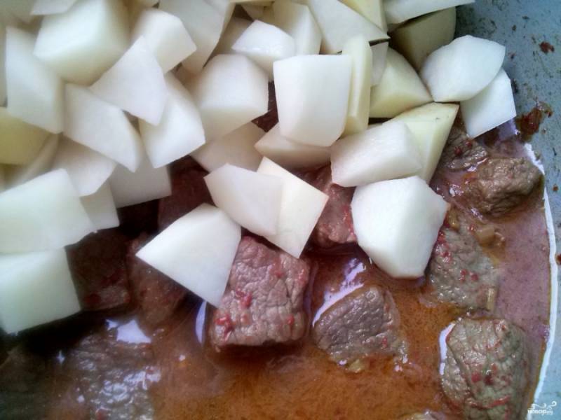 Очищенный картофель порежьте кубиками немного меньше мяса. Томаты, перец горький и сладкий нарежьте кусочками. Все овощи выложите к мясу, добавьте томатную пасту, налейте бульон, так чтобы он на палец не покрывал гуляш. Посолите по вкусу и тушите при закрытой крышке до готовности картофеля.