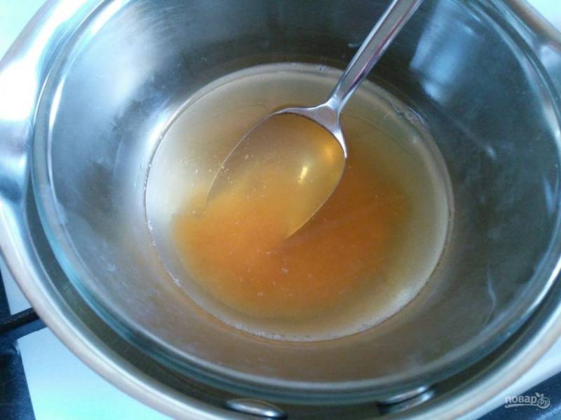 В термостойкую ёмкость выложите мёд и влейте воду, поместите смесь на водяную баню, нагревайте до растворения мёда, перемешивая массу ложкой.