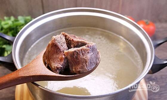 Варёное мясо отделите от кости и нарежьте. Добавьте его обратно в суп.