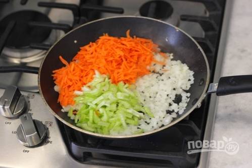 На сковороде разогрейте масло. Обжарьте в нём мелко нарезанный лук 5 минут. Затем добавьте к нему натёртую морковь и нашинкованный сельдерей. Жарьте овощи, помешивая, 4 минуты. После зажарку отправьте в кастрюлю.