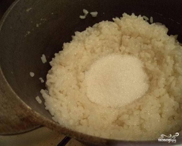 Снимите крышку, сделайте в рисе воронку и всыпьте сахар. Добавьте изюм. Засыпьте сахарный песок и изюм без косточек рисом.
