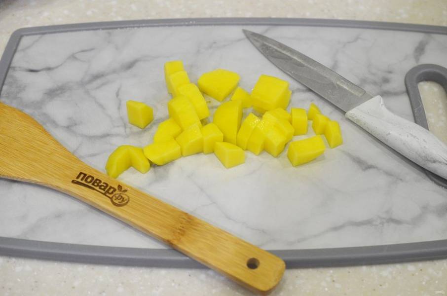 2. Вскипятите 2 л воды или бульона. Картофель почистите, нарежьте и добавьте в кастрюлю. Варите минут 7.