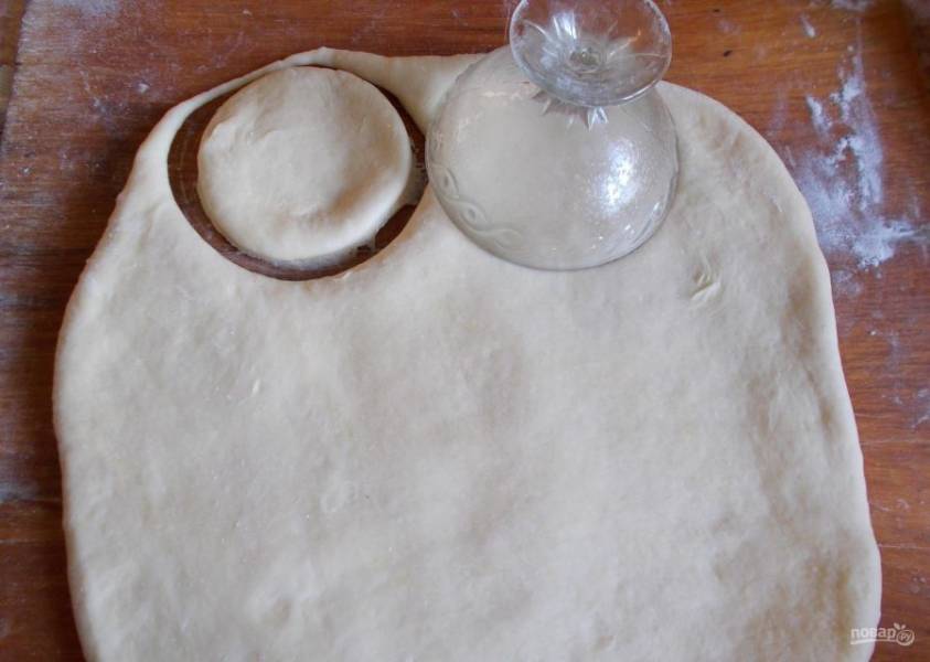 Готовое тесто раскатайте в лепёшку в 1 см толщиной. Вырежьте из него изделия примерно в 10 см диаметром.