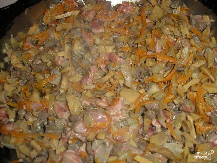 Очистите лук и морковь. Нарежьте лук, а морковь натрите на крупной тёрке. Начинайте обжаривать овощи на растительном масле. Тем временем вымойте и некрупно нарежьте сердца и печень. Обжарьте мясо на сковороде до полуготовности. Затем вымойте и нарежьте шампиньоны, отправьте их на сквороду и обжарьте.