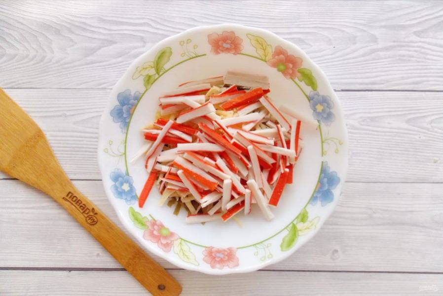 Крабовые палочки нарежьте соломкой и добавьте в салат.