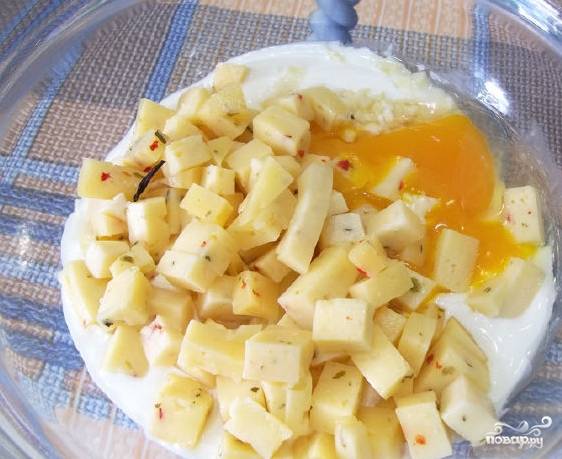 4. Нарежьте небольшими кубиками твердый сыр, выложите его к сметане с чесноком. Затем разбейте яйцо и содержимое влейте в сметанную смесь. 
