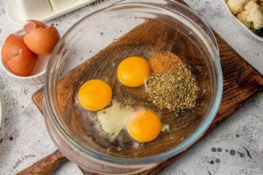 Яйца вбейте в подходящую посуду, добавьте по вкусу соль и черный молотый перец. Для аромата добавьте сушеный орегано. Если не нравится орегано, то не добавляйте или добавьте те специи, которые нравятся вам. Перемешайте  массу венчиком, чтобы соединились белки с желтками и приправами. 