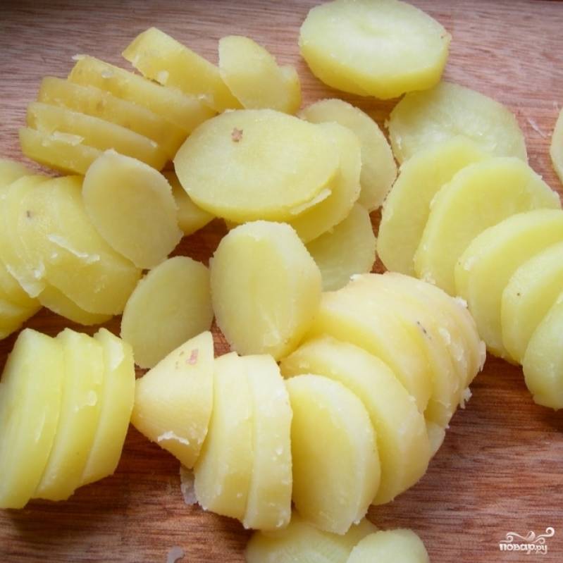 Приготовить картофельную запеканку очень легко. Для начала нужно сварить картофель в мундире до полной готовности, остудить, почистить и нарезать на кружочки толщиной приблизительно 0,5 см.