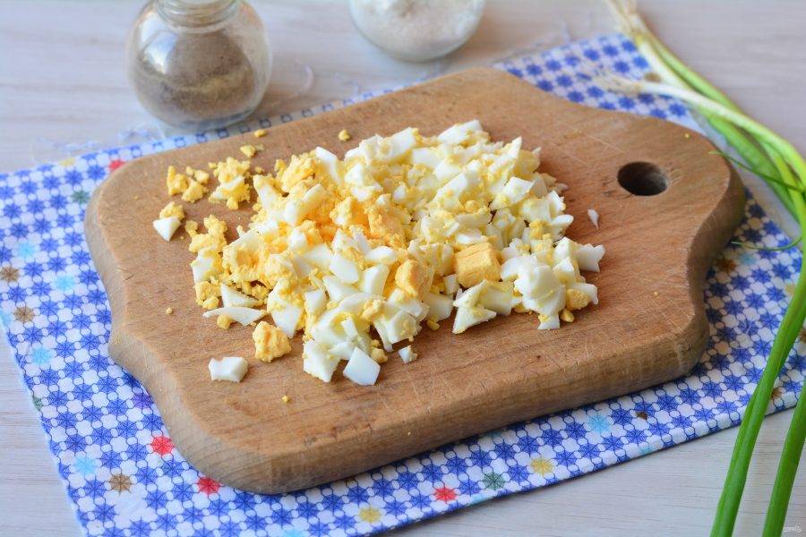 Сварите вкрутую куриные яйца. Нарежьте их кубиками.