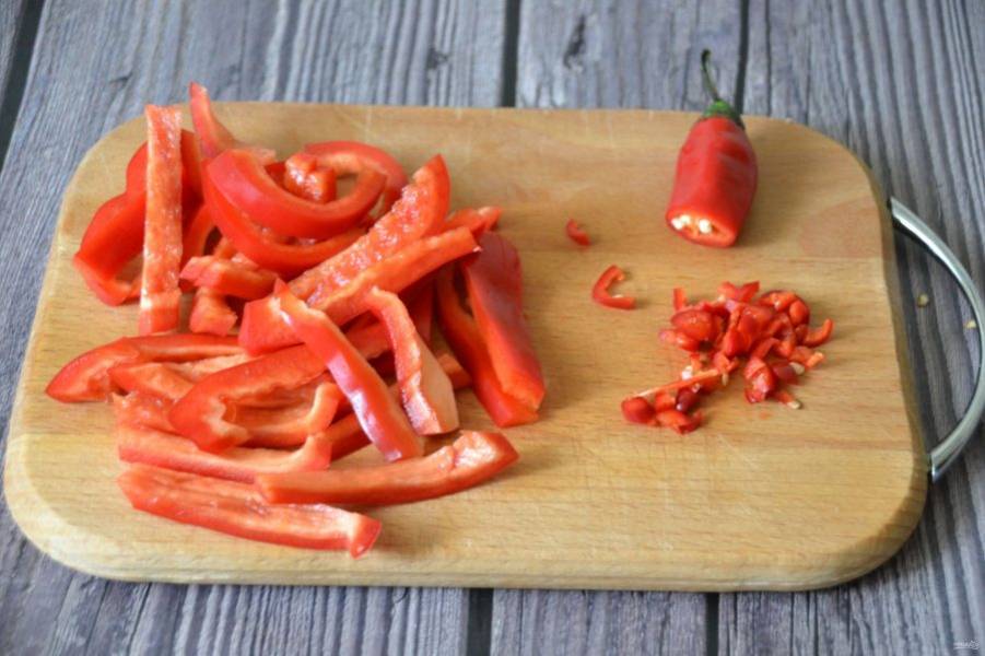 Нарежьте брусочками болгарский перец, измельчите половинку острого перца.