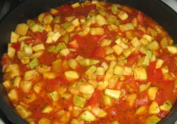 Разогреваем в сковороде растительное масло и обжариваем кабачки, примерно 10 минут, постоянно их помешивая. Затем добавляем мелко порезанные томаты, томатную пасту, аджику и измельченный чеснок. Перемешиваем и тушим на медленном огне еще 20 минут.