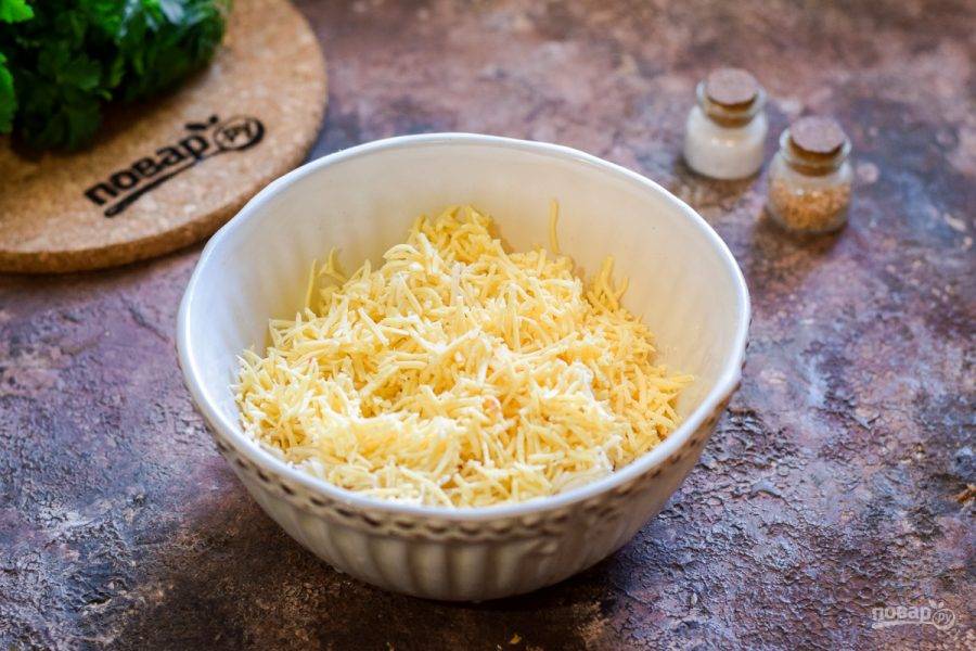 Твердый сыр натрите на мелкой терке и добавьте в миску к плавленому сыру.