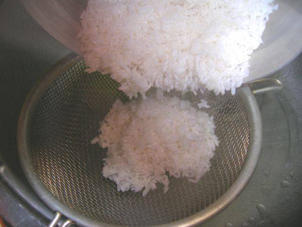 3. Когда крупа закипит, сливаем воду через дуршлаг. После этого рис перекладываем снова в кастрюлю.