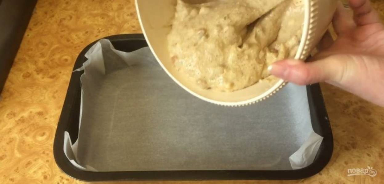Выложите в тесто хорошо промытый изюм и снова перемешайте. Выложите тесто в прямоугольную форму, покрытую пергаментом, и разровняйте. 