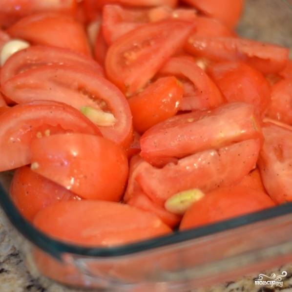 Берем форму для запекания, внахлест выкладываем помидоры. Сверху сбрызгиваем оливковым маслом. Туда же добавляем очищенный и крупно нарезанный чеснок. Солим и перчим.