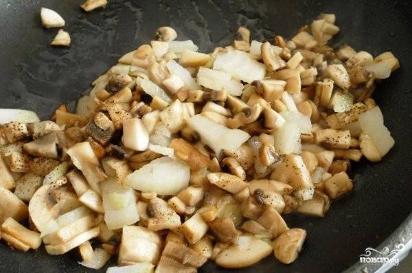 Очищенный лук мелко нарезаем и добавляем к грибам на сковороде. Обжариваем до мягкости и прозрачности лука.