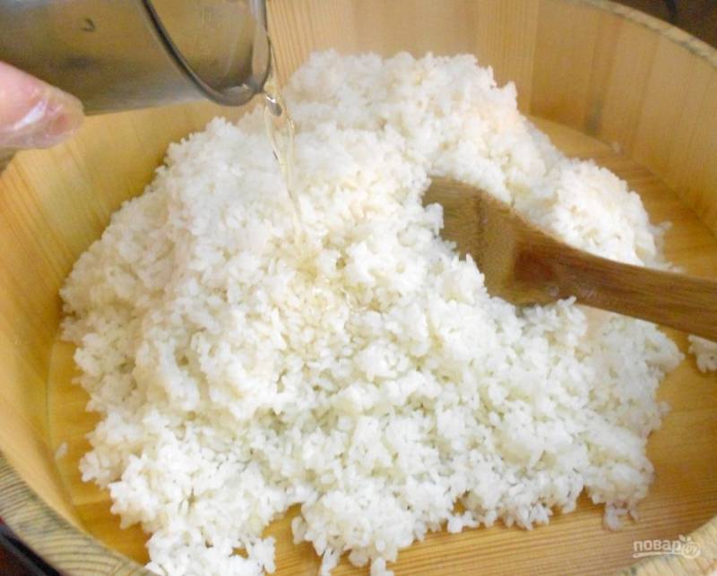 7. Поливаем рис готовым соусом и аккуратно перемешиваем деревянной лопаткой. На 1 кг готового риса понадобится 125-200 мл готового соуса. В холодный рис заправка не добавляется — испортятся вкусовые качества. Как только вы переложили рис, сразу добавляйте "суши-су". 