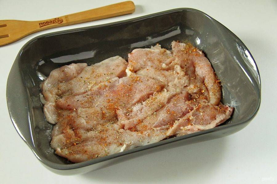 Куриное филе разрежьте вдоль на тонкие пластины и сложите внахлест в форму для запекания. Форму предварительно смажьте маслом. Посолите филе и посыпьте любимыми специями.
