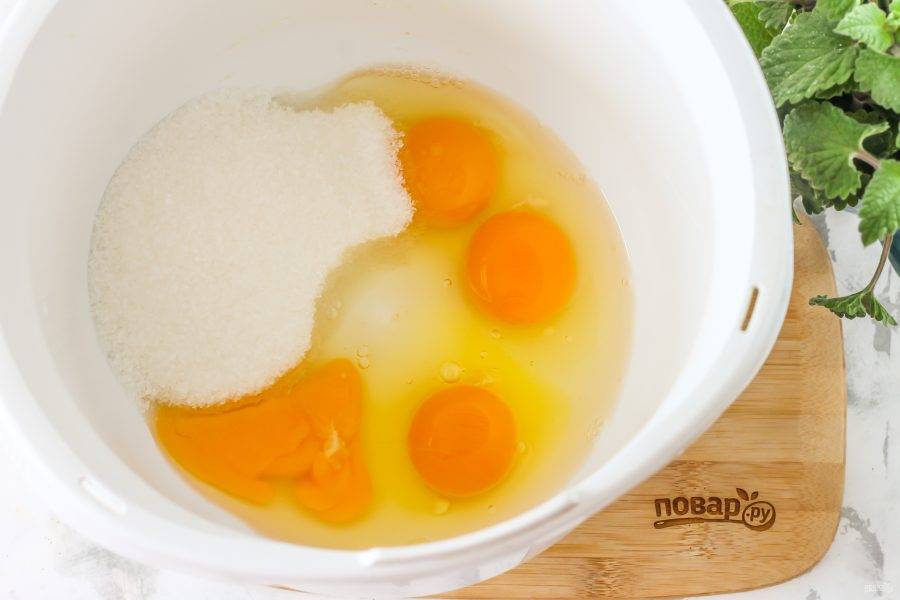 Куриные яйца вбейте в чашу кухонного комбайна, всыпьте туда же 1 стакан сахарного песка и соль, тщательно взбейте в течение 5 минут на самой высокой скорости техники в пышную массу.