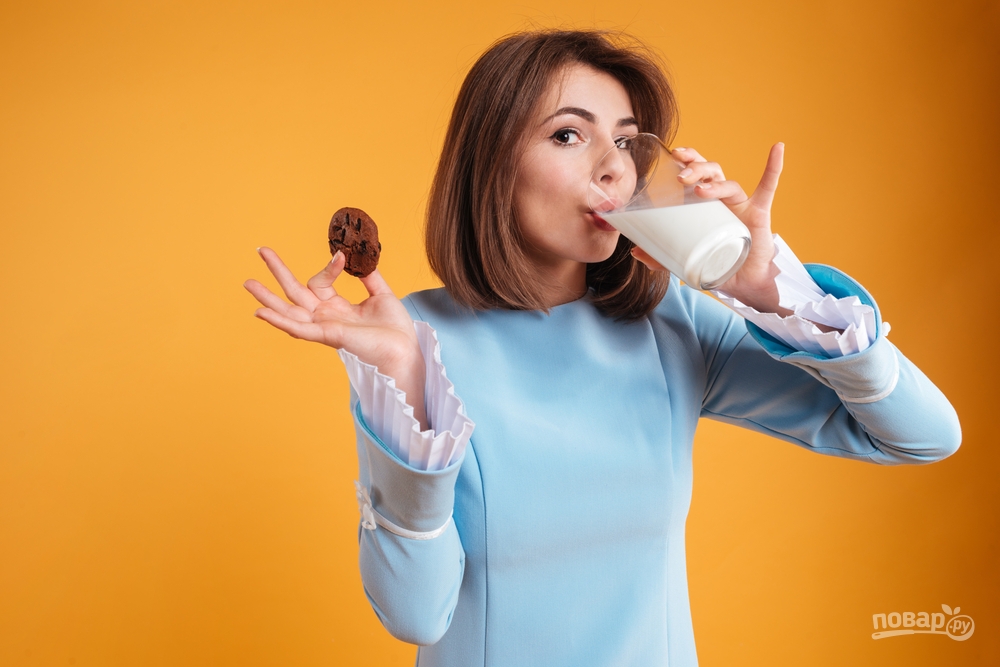 Женщина пьет молоко с печеньем
